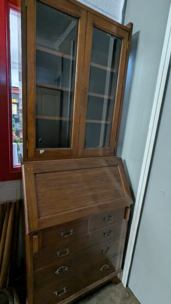 Antique wooden display cabinet with glass doors, brass handles, and adjustable shelves.