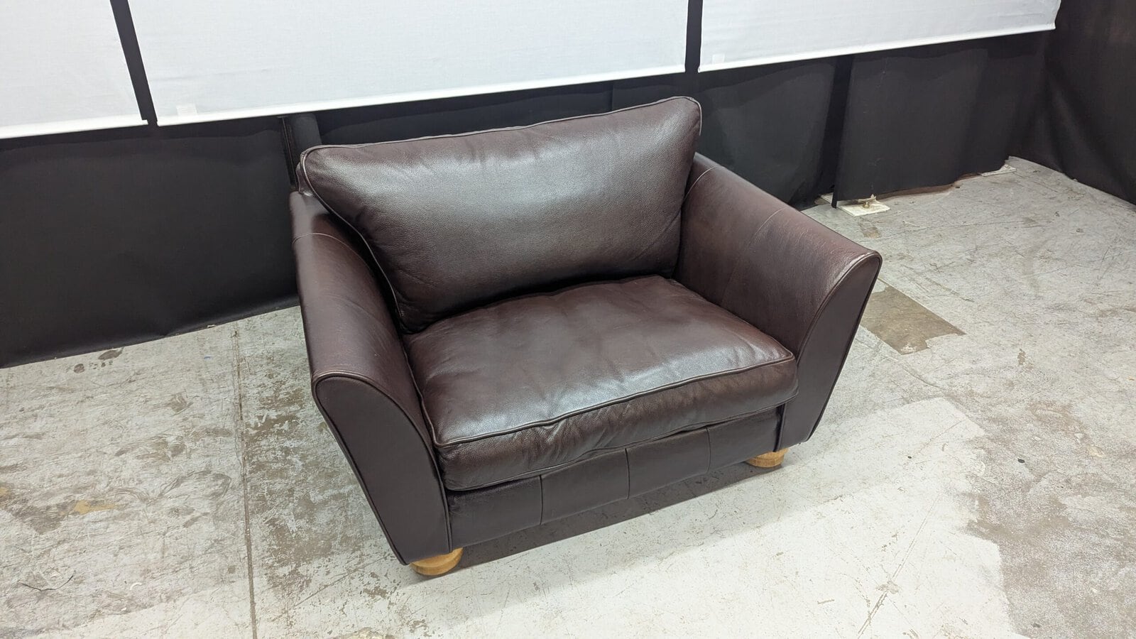 Modern brown leather 2-seater sofa Brown leather 2-seater sofa with sleek design and wooden feet.