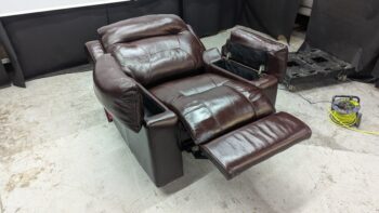 Recliner sofa in rich brown leather with adjustable footrest and plush cushions. Perfect for relaxing and adding style to your living space.