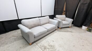Light grey 2-seater sofa and matching armchair, contemporary style, in a showroom setting.