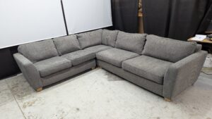Modern grey corner sofa with plush cushions and wooden feet.
