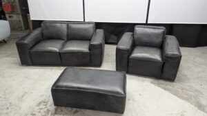 Modern black leather sofa set with matching ottoman.