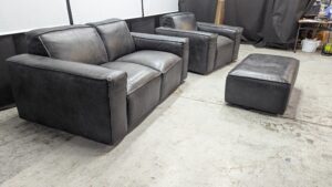Modern black leather sofa set with matching ottoman.