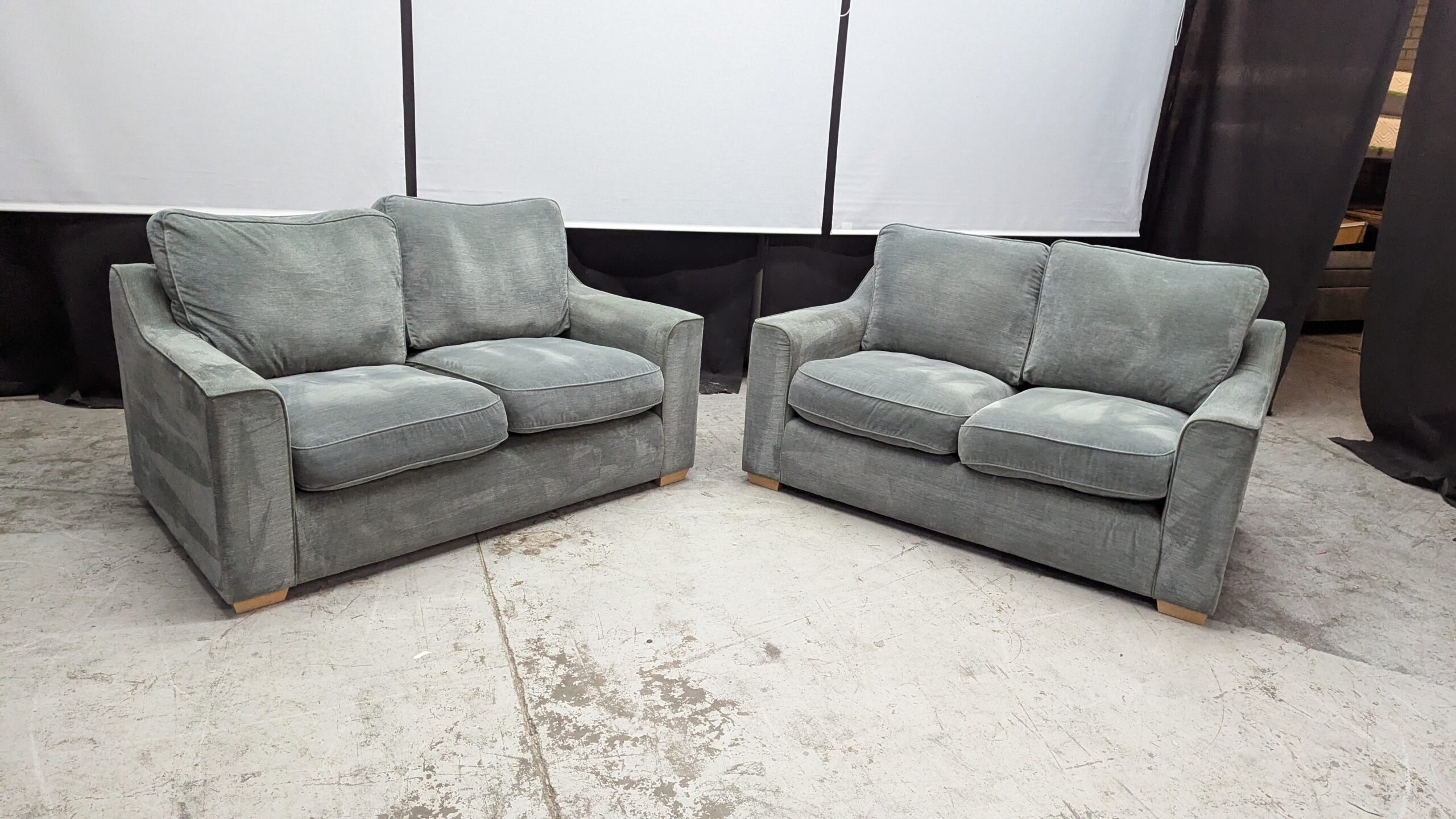 Modern Grey Fabric 2-Seater Sofas Two grey fabric 2-seater sofas with plush cushions and wooden legs.
