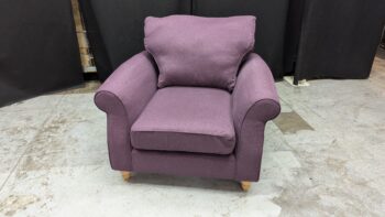 Armchair in purple fabric with plush cushions and wooden feet.